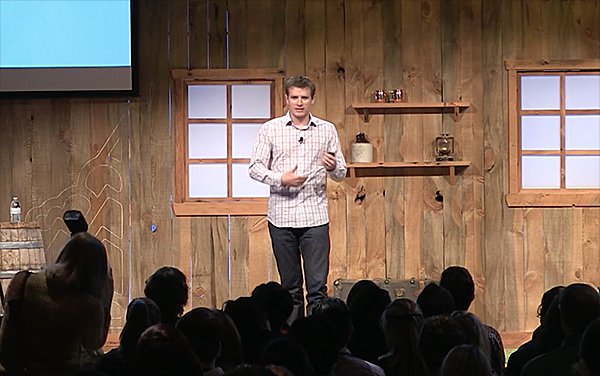 Nathan Barry presents his conference talk in front of a log cabin background at the Pioneer Nation conference.